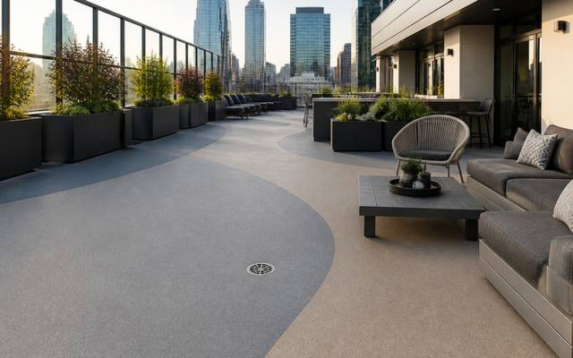 Rooftop patio finished in grey rubber surfacing with lounge seating and a skyline behind